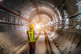 An engineer wearing a hard hat stands in a underground railway tunnel