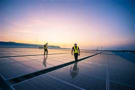 Two workers inspect a solar panel installation on a factory roof