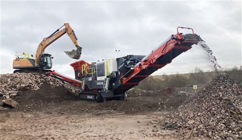 A sandvik mobile crusher being loaded by an excavator
