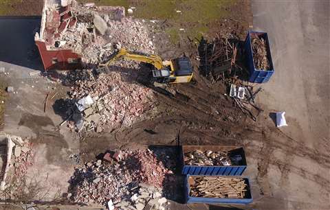 Aerial photo of an excavator as it demolishes a house with materials sorted for reuse